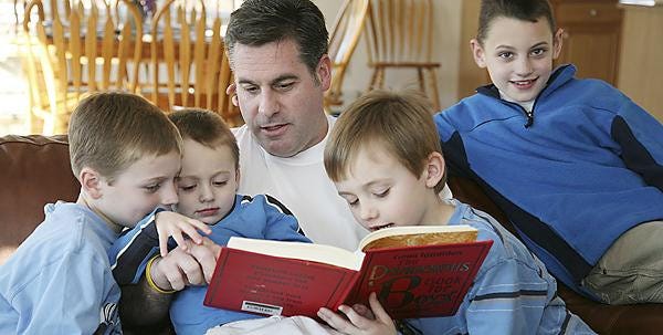 Don Vendetti looks through “The Dangerous Book for Boys” with his four sons, from left, Craig, 7, Corey, 2, Christian, 6, and Cameron, 9.