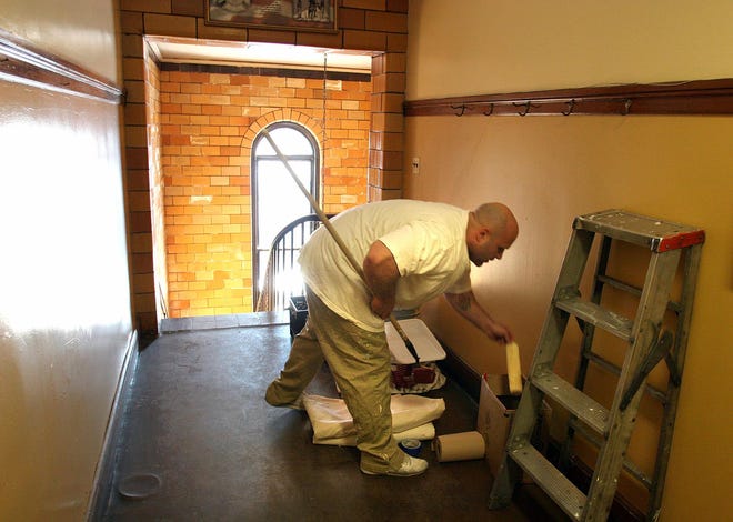 William Fox mixes some paint in a firehouse hallway he painted at Weymouth Fire Department Headquarters. Inmates from the Norfolk County Jail painted the building's interior, which had not been painted in more than 20 years.