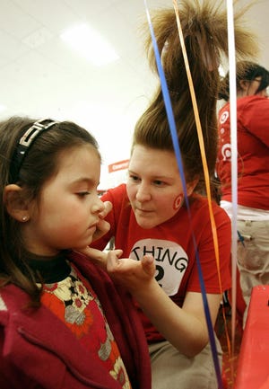 Four-year-old Delanie MacDonald gets her face painted by Sarah Naughton, 17, of Whitman during a celebration of Dr. Seuss’ birthday at the Target store in Stoughton on Sunday afternoon. Naughton was dressed as Thing Two, a character in the Seuss book “The Cat in The Hat.”