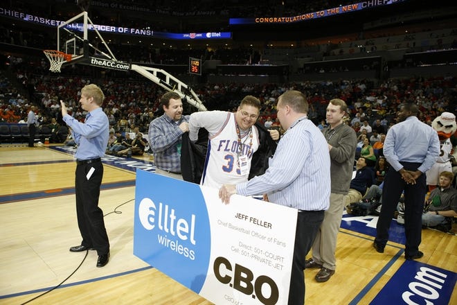 Gator fan and Gainesville resident Jeff Feller puts a sports coat on over his vintage Dametri Hill jersey upon being crowned 'Chief Basketball Officer of Fans' Thursday at the ACC Tournament. Chad Brokaw, the "cool guy" in Alltel commercials, far left, was at Feller's side for the announcement.
