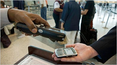 A security worker scanning the image of a bar code on a BlackBerry as part of Continental Airlines’ electronic boarding pass pilot program.