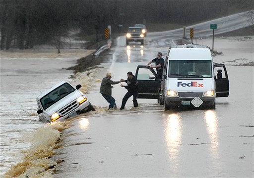Fedex driver Jay McMullin helps 78-year-old Odell Bunch into the delivery truck after Bunch's Ford Ranger was swept off of Hwy 34 by flood waters on Tuesday, March 18, 2008. Torrential rains that hammered southern Missouri caused widespread flooding Tuesday that left two people dead, hundreds homeless, closed nearly 200 roads and sent propane tanks and debris spiraling down lowlands turned into raging rivers.