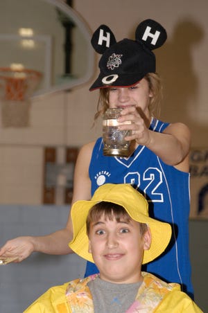Central Grade School eighth-grader Brooke Bambrick, wearing the H2O cap, holds a jar of water over eighth-grader Nick Lauss’s head during an experiment on air pressure.