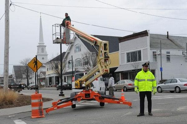 Barnstable police Sgt. Ben Baxter helps direct traffic at the intersection of Old Colony Road and Main Street in Hyannis yesterday while a work crew replaces light bulbs.