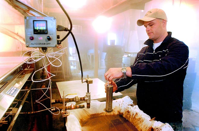 Christopher Schoff of Victor constantly checks the thickness of the maple syrup as it comes out of the evaporator pans.