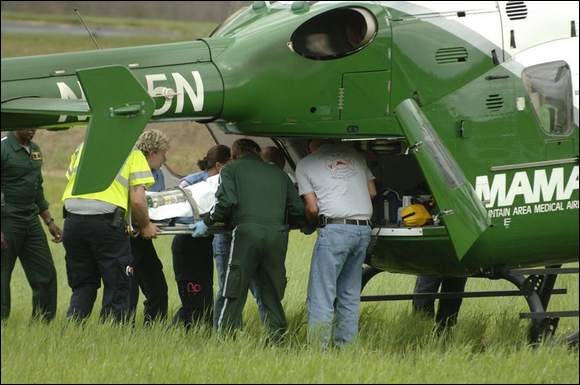 Emergency officials load Bill McKay onto the Mountain Area Medical Airlift on Friday at a field near the intersection of Tracy Grove Road and Howard Gap Road.
