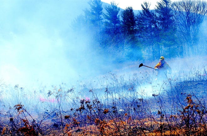 A firefighter combats a 10-acre brush fire that broke out on Hicks Road near Seneca Point Road in South Bristol Thursday, when a planned burning of grape-brush grew out of control due to high winds.