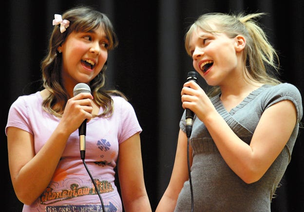 Rachel Cabrera, left, and Vanessa Bannister, both sixth-graders at Lombard Middle School, sing along to “A True Friend” during Friday afternoon’s talent show in the school auditorium. Eleven different acts showed off their entertainment skills during the all-school assembly.