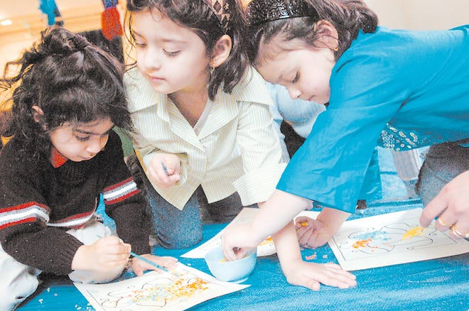 From left, Ronak Singh, 3, Alisha Semy and Sarah Semy, both 4, create their own rangoli, or decorative sand painting, during a celebration of the Indian festival of Holi at Cary Memorial Library last week.