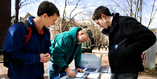 Young Obama student volunteers Mike Stratta, left, and Christo Logan, right, assist University of Pennsylvania worker Dave Munson, 45, fills up a voter registration form on University of Pennsylvania campus, in Philadelphia on Thursday, March 20, 2008. In Philadelphia, where more than 100,000 live in the metropolitan area, Obama volunteers with voter registration forms in hand were spotted on campuses and at train station around Philadelphia's University City shouting out to their peers and passersby to register.