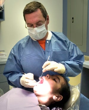 Dr. Luis Estrada works on Thalia Ramirez, 12, at the Marion County Health Department's dental clinic in Ocala on Wednesday. Apart from the Health Department, only two area dentists accept pediatric patients with Medicaid, given the low reimbursements and paperwork involved.