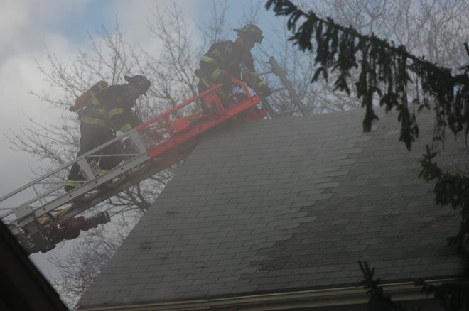 Wellesley firefighters climb a ladder to the roof of a home at 23 Hastings St. shortly after a fire was extinguished yesterday. Nobody was injured in the blaze, though a dead dog, found in the basement, apparently died of smoke inhalation.