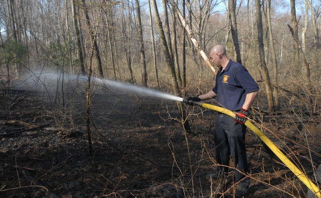 Firefighter Tim Devoll wets down part of a 20-acre brush fire Friday afternoon at the end of Kato Drive in Sudbury.