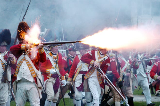 A British Redcoat fires a shot during a Revolutionary War reenactment at the Battle Green in Lexington on Monday.