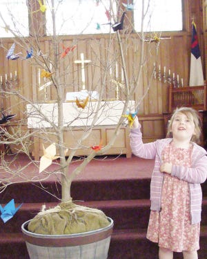 PHOTO SUBMITTED BY JAN PARKER
PEACE TREE: Margret Philie proudly points to one of the 1,000 paper peace cranes being made by members of the congregation to decorate the Chinese dogwood as a symbol of peace and luck.
