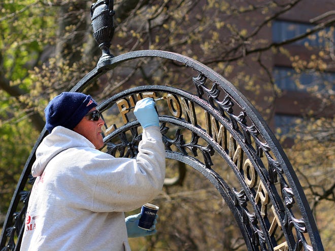 Joe Mariano of the Quincy Cemetery Department puts fresh gold paint on the wrought iron arches at a Hancock Cemetery entrance in Quincy Square.