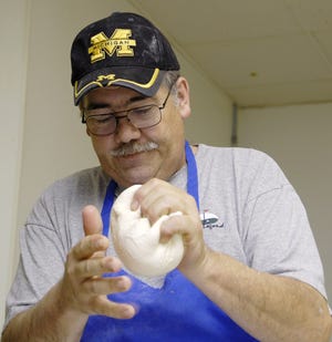 Mark Bearss, general manager of the Pizza Factory in Adrian, prepares pizza dough.