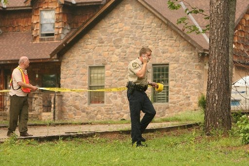 A member of the Duncanville Volunteer fire department, left, and Cpl. Mark Dill of the Tuscaloosa County Sheriff’s Office roll out crime scene tape at the shooting scene Saturday.