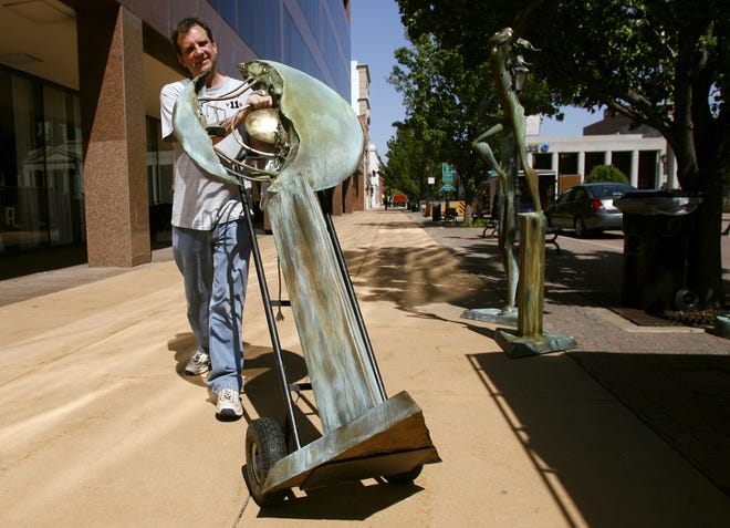 Tom Yano of Vermilion, Ohio, moves a sculpture into his tent Friday in preparation for this weekend’s Old Capitol Art Fair. Yano has shown work at the fair for 18 years.