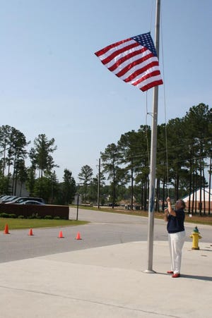 Richmond Hill Primary School counselor Donna Jean Pecenka raises the American flag, which flew over both Washington, D.C. and Iraq, at Richmond Hill Primary School May 15. (Allison Bennett Dyche/Bryan County Now)