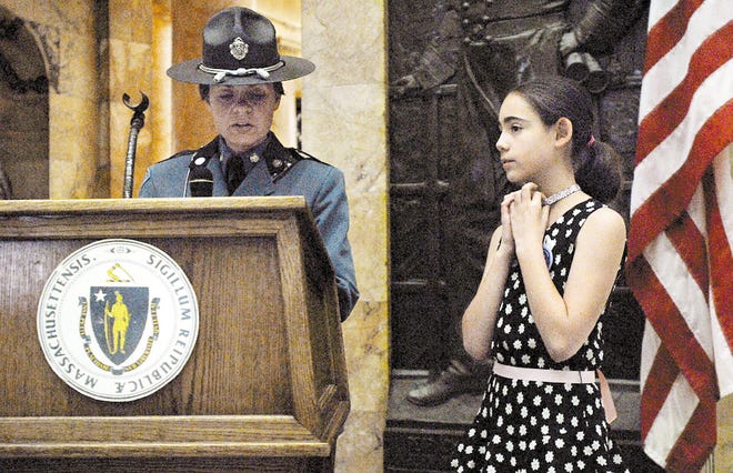 Stephanie Ward, a fifth-grader at Marlborough Intermediate Elementary School, listens as state Trooper Nicole Morrell announces Stephanie's first-place finish in an Amber Alert poster contest at the State House yesterday.