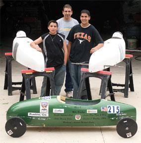 CHIEFTAIN PHOTO/BRYAN KELSEN Matt, 12, and Mario, 16, Vasquez stand with their father Paul and the two masters division Soap Box Derby cars that they are building. The car in the foreground is Matt's championship super stock division car from last year.
