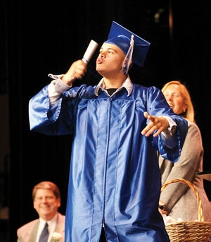 Jacob Flores kisses his diploma during the Adrian Adult Education commencement program Friday evening at the Croswell Opera House in Adrian.
