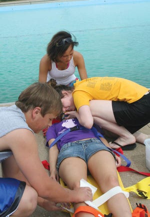 Monmouth city pool lifeguards, clockwise from left, Shane Creighton, Jalynne Young and Mandy Lyle, act out a mock trauma accident on Andrea Windbigler at the pool. The staff is preparing for the pool season, which begins Saturday.