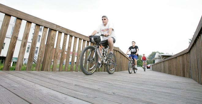 Tim Borotkanics, Chance Wilging and Lori Frase, all of Doylestown, ride out of Canal Fulton along the towpath boardwalk after a quick ice cream break at the Cherry Street Creamery.