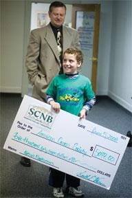CHIEFTAIN PHOTO/BRYAN KELSEN Retzio Gredig, 8, smiles as he holds a check from Southern Colorado National Bank while bank President Keith Varner looks on Thursday afternoon at City Hall. The money was raised as part of the upcoming Relay for Life which benefits the American Cancer Society.