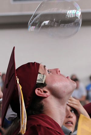 Algonquin Regional High School graduate Andrew Clementi blows on a soap bubble to keep it aloft during yesterday's commencement.