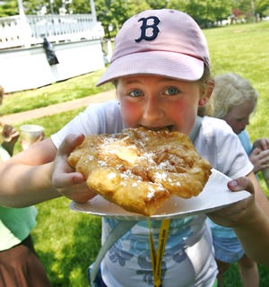 Amanda Colwell, 10, of East Bridgewater takes a bite of fried dough during a fundraiser family Fun Day at the East Bridgewater Common on Saturday afternoon.