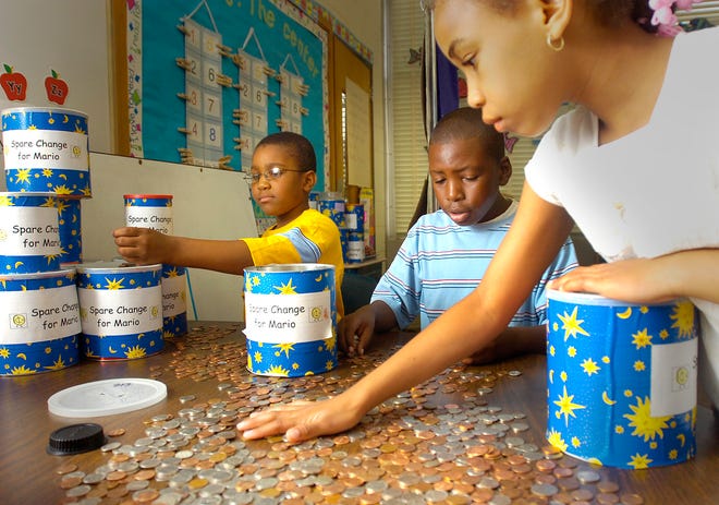 Donovan Elementary School students, from left, Zacari Howard, Tarence Irby and Grace Milord count change they collected to help their classmate, Mario Alestock, who has a rare, inherited disease that leads to progressive brain damage.
