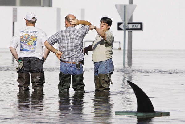 JULIE JACOBSON/The Associated Press
A fake shark's fin, set afloat by a local businessman whose store basement was flooding, drifts along a flooded Front Street as city employees discuss sandbagging efforts Tuesday in Burlington, Iowa.