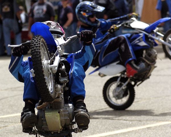 Brothers Kyle and Cody Ives do stunts in the Laconia City Hall parking lot before entering the Ball of Steel to race during Laconia Motorcycle Week activities.