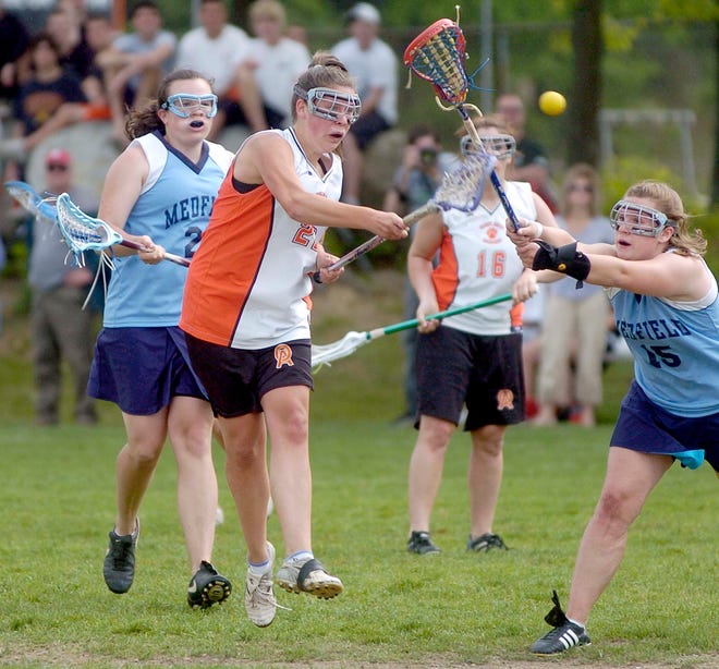 Oliver Ames forward Alicia Brockman, center, fires a shot for a goal against Medfield during the girls lacrosse tournament last month.