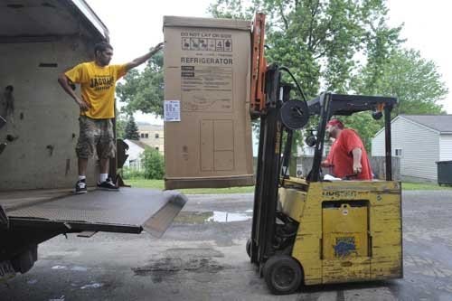 The Times/CHRISTINA BAIRD Mike Riccardi, left, assistant warehouse manager at A. K. Nahas in Vanport Township, and warehouse manager Bob Kotoff Sr., unload crates for storage at the Vanport furniture and appliance store Friday afternoon.