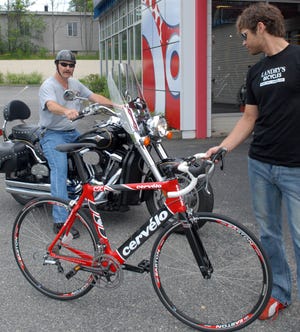 Andrew Palmgren, right, sales manager at Landry's Bicycles at 790 Worcester Road in Natick, holds up a Cervelo bike as Maynard resident Steve Hewins leaves on his Vulcan Kawasaki. Hewins also rides bicycles.