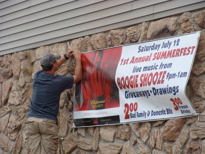 Broadcasting the news: Kep’s Sports Bar co-owner Brock Heider hangs a banner outside the bar to advertise Saturday’s grand opening festivities. The fun starts at 4 p.m.