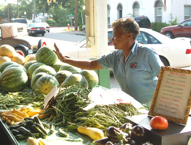 Martha Dicks shows a customer the assortment of locally-grown produce she has for sale at her booth at the Aiken County Farmers Market.