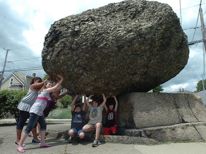 Students from Wixon Elementary School in Fall River pretend to hold up the Rolling Rock, a boulder at the intersection of County Street and Eastern Avenue.