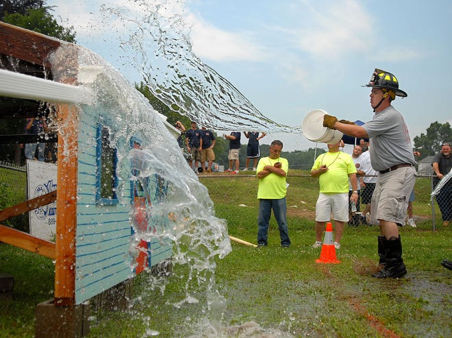 Jewett City firefighter and driver Ken Comfort throws a bucket of water onto the roof of a fake house during the Bucket Brigade event of a firefighters muster hosted by the Taftville Volunteer Fire Department Saturday, July 19, 2008, at the Taftville Little League field. During this event firefighters fill buckets with water and throw it on the roof where it rolls down a gutter and collects in a barrel. The fastest team to fill the barrel wins the event.
