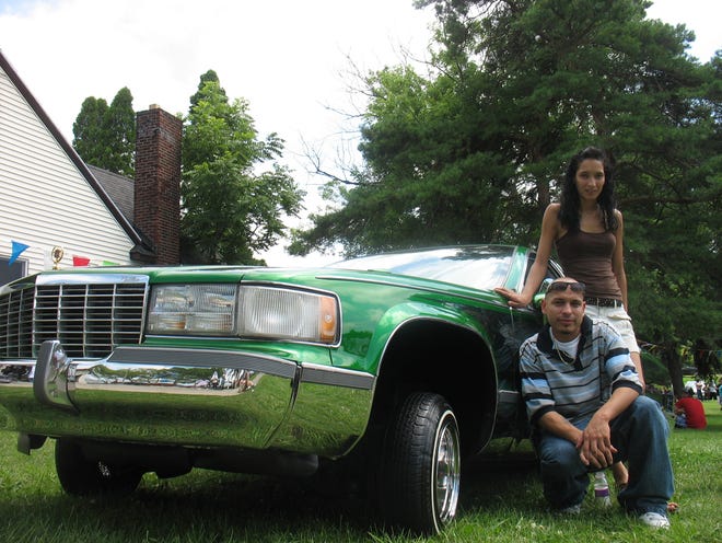 Adrian Contreras, 27 of Wyoming and his girlfriend pose with Contreras’ car, a 1993 Cadillac Fleetwood, at the Low-Pez car show Sunday in Holland.