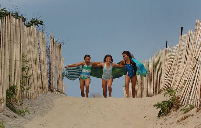 Courtney Keyes, 10, Victoria Foley, 9, and Marisa Mulvey, 10, run down the sandy path at Rexhame Beach in Marshfield. Rexhame’s waves are ideal for boogie-boarding.