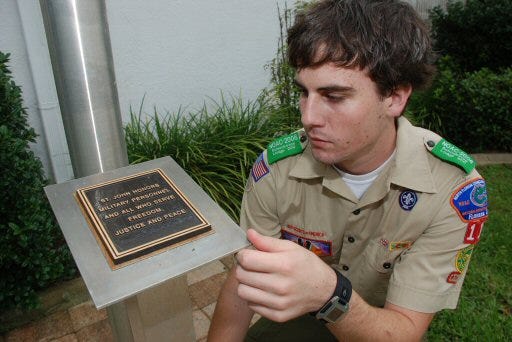 Eagle Scout Chuck Wincek makes some adjustments to the plaque at the base of the flag pole monument he built for his Scout project in front of the St. John Luteran Church in Summerfield.