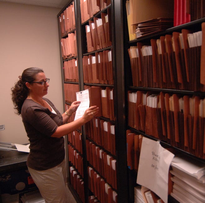 Lisa Cook looks for some files in the Finance Department. County officials hope a flexible work plan saves on utilities.