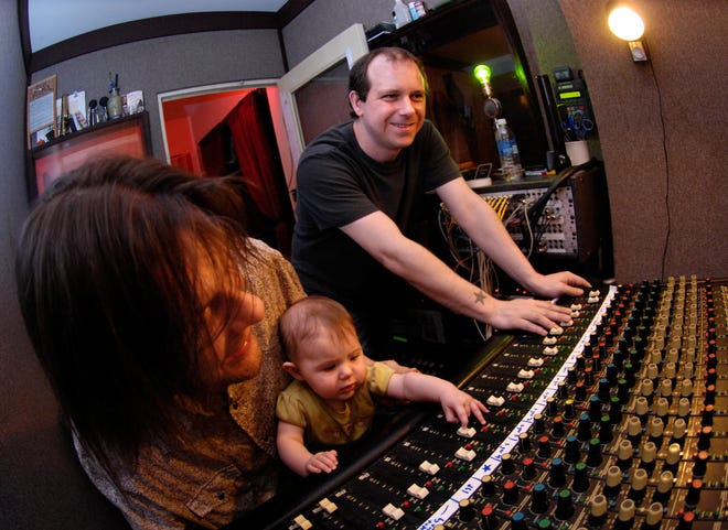 Dave Moe, left, holding his 6-month old daughter, Teghan Moe, along with Jeff Gregory, right, are the co-owners of Chocolate Ladyland Studio a music recording studio at 516 W. Main St. in Peoria.