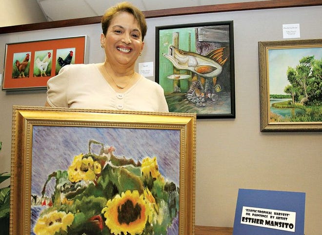 La pintora Esther Mansito posa con uno de sus cuadros, ”Sunflower Basket’, que estará exhibiéndose junto a otras de sus obras en la galería del Bank of America, Downtown Ocala.