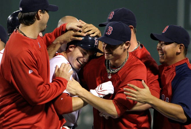 Jed Lowrie (center) is surrounded by gleeful teammates after driving in the winning run on Friday.