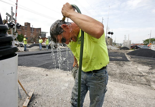Buddy Harvey of Morse Driveways cools off while working on the paving at the railroad tracks on Adams Street between Ninth and 11th streets. “We just hurry up and get it done in order to get out of this heat,” Harvey said.
